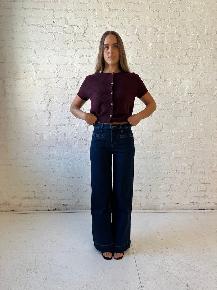 Woman wearing dark wash high waisted, wide leg jeans with sweater top. 
