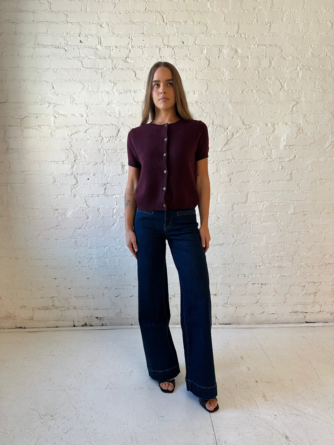 Woman wearing dark wash high waisted, wide leg jeans with sweater top. 