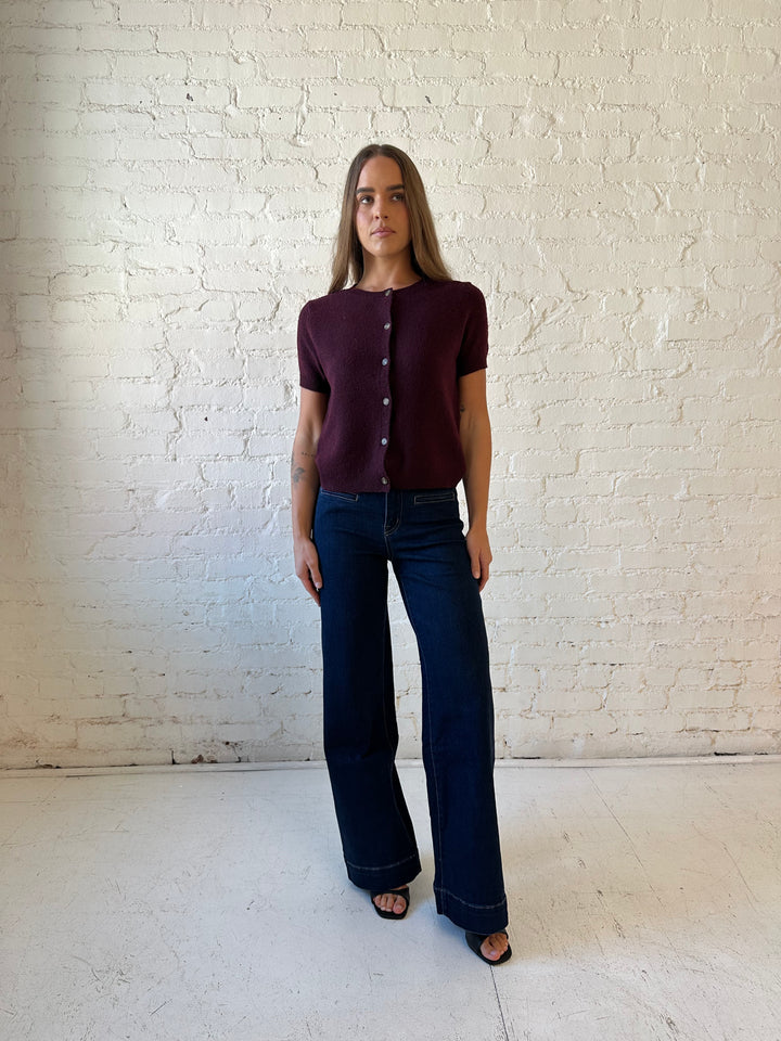 Woman wearing dark wash high waisted, wide leg jeans with sweater top. 