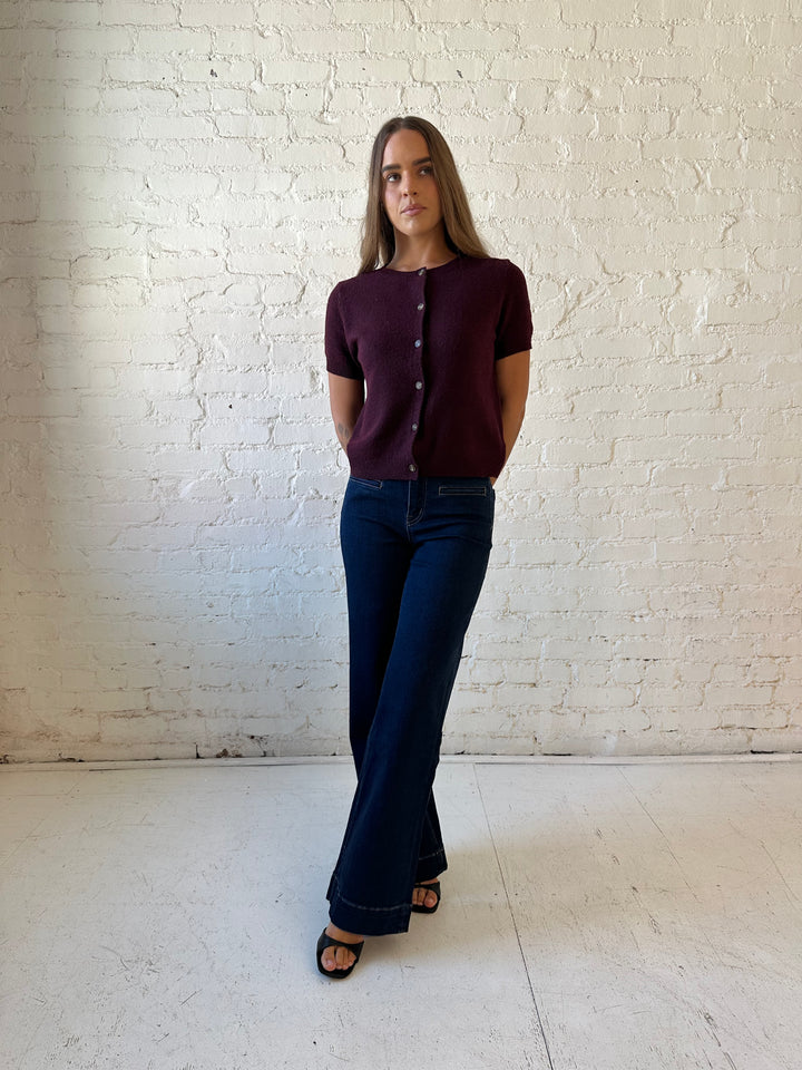 Woman wearing dark wash high waisted, wide leg jeans with sweater top. 
