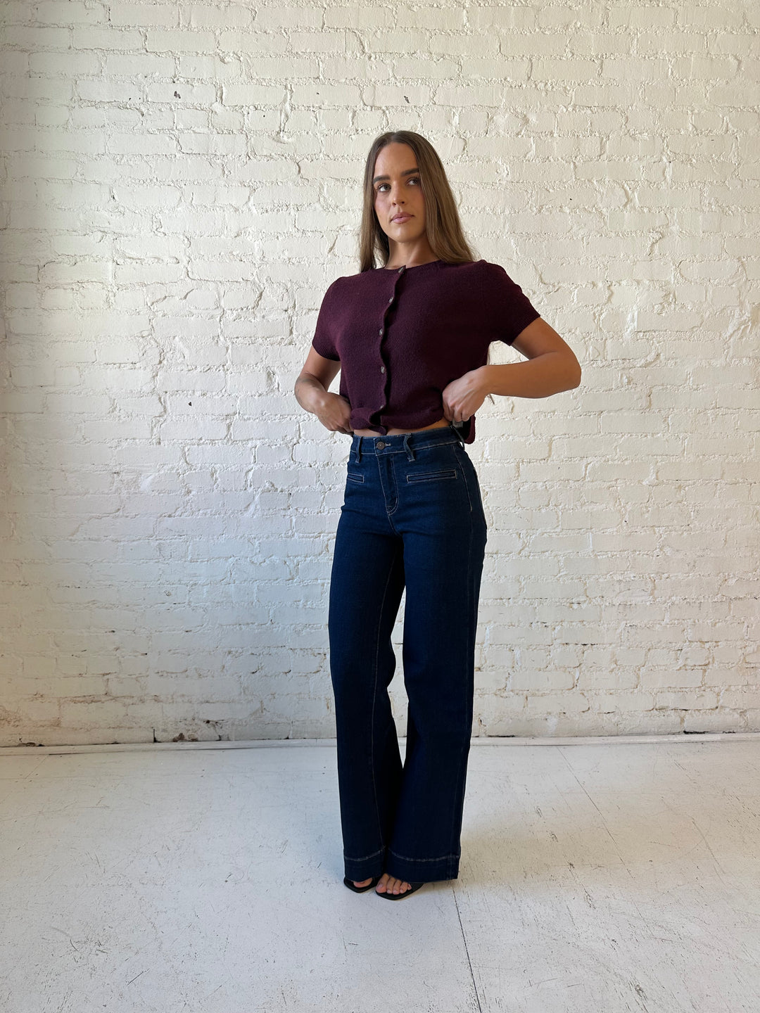 Woman wearing dark wash high waisted, wide leg jeans with sweater top. 