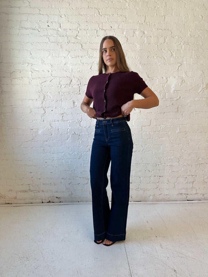 Woman wearing dark wash high waisted, wide leg jeans with sweater top. 