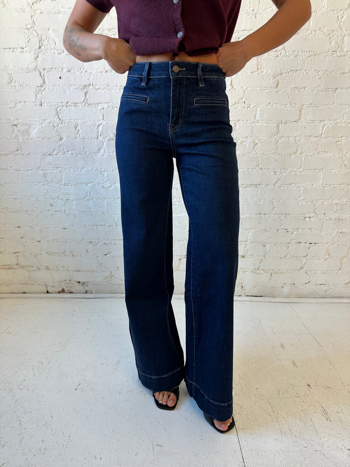 Woman wearing dark wash high waisted, wide leg jeans with sweater top. 