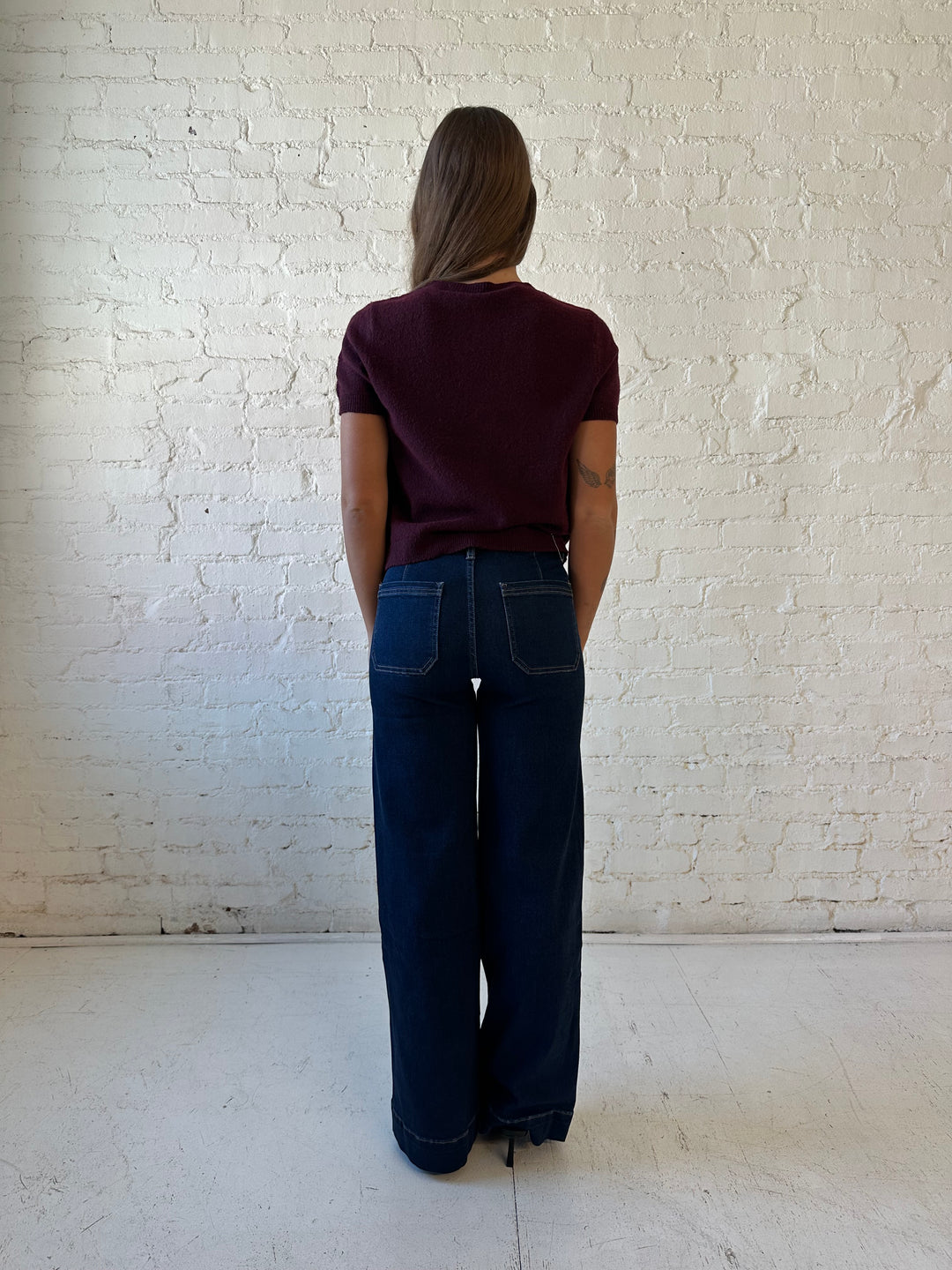 Woman wearing dark wash high waisted, wide leg jeans with sweater top. 
