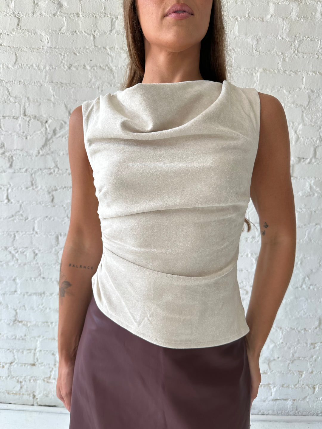Woman wearing light grey suede top with a burgundy leather skort. 