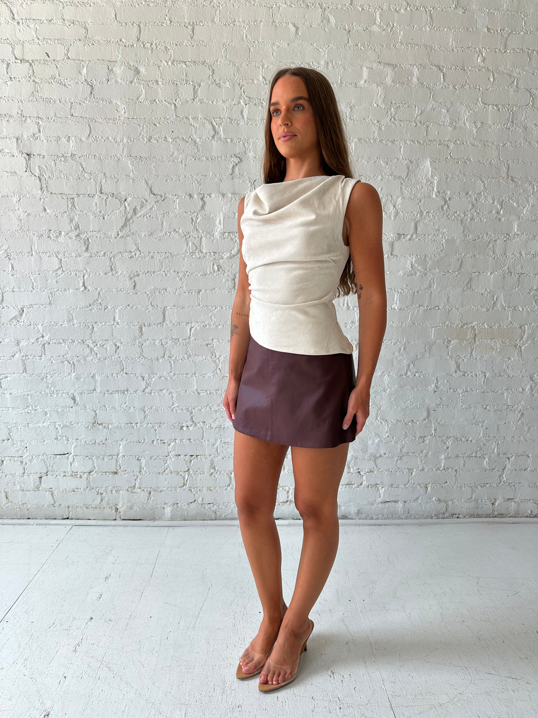 Woman wearing light grey suede top with a burgundy leather skort. 