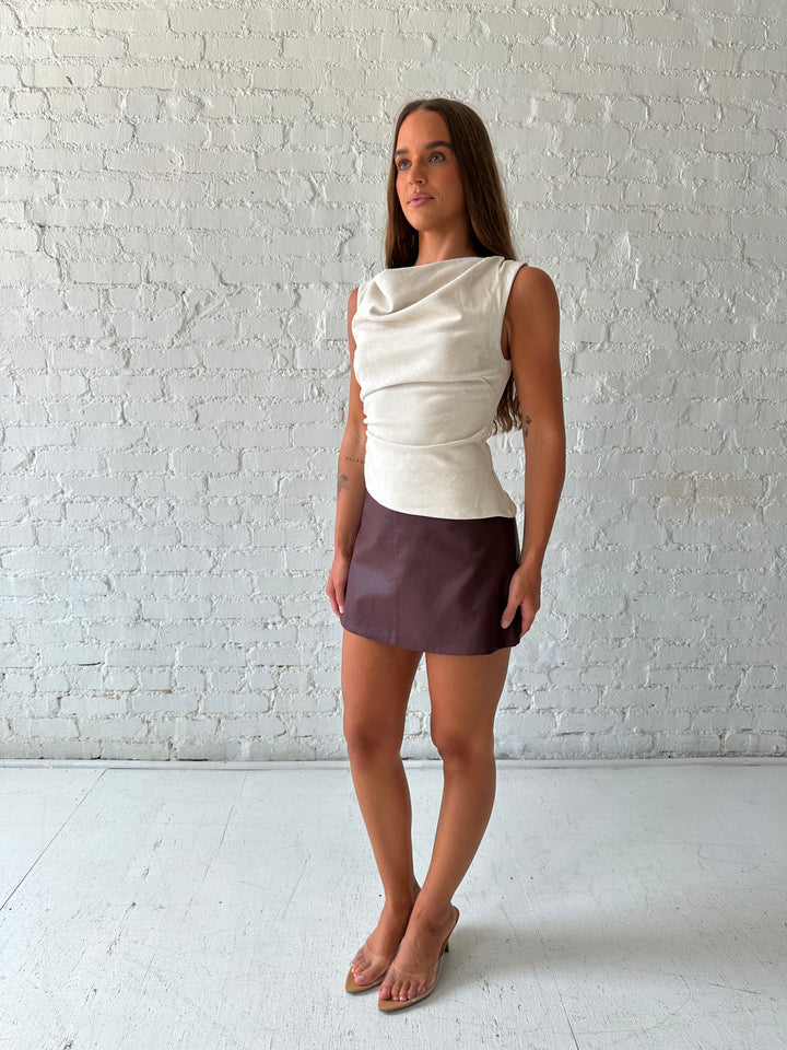 Woman wearing light grey suede top with a burgundy leather skort. 