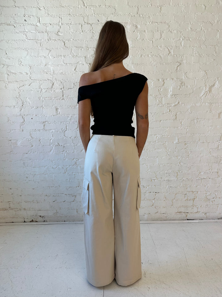 Woman wearing black knit off the shoulder top with khaki colored cargo pant. 