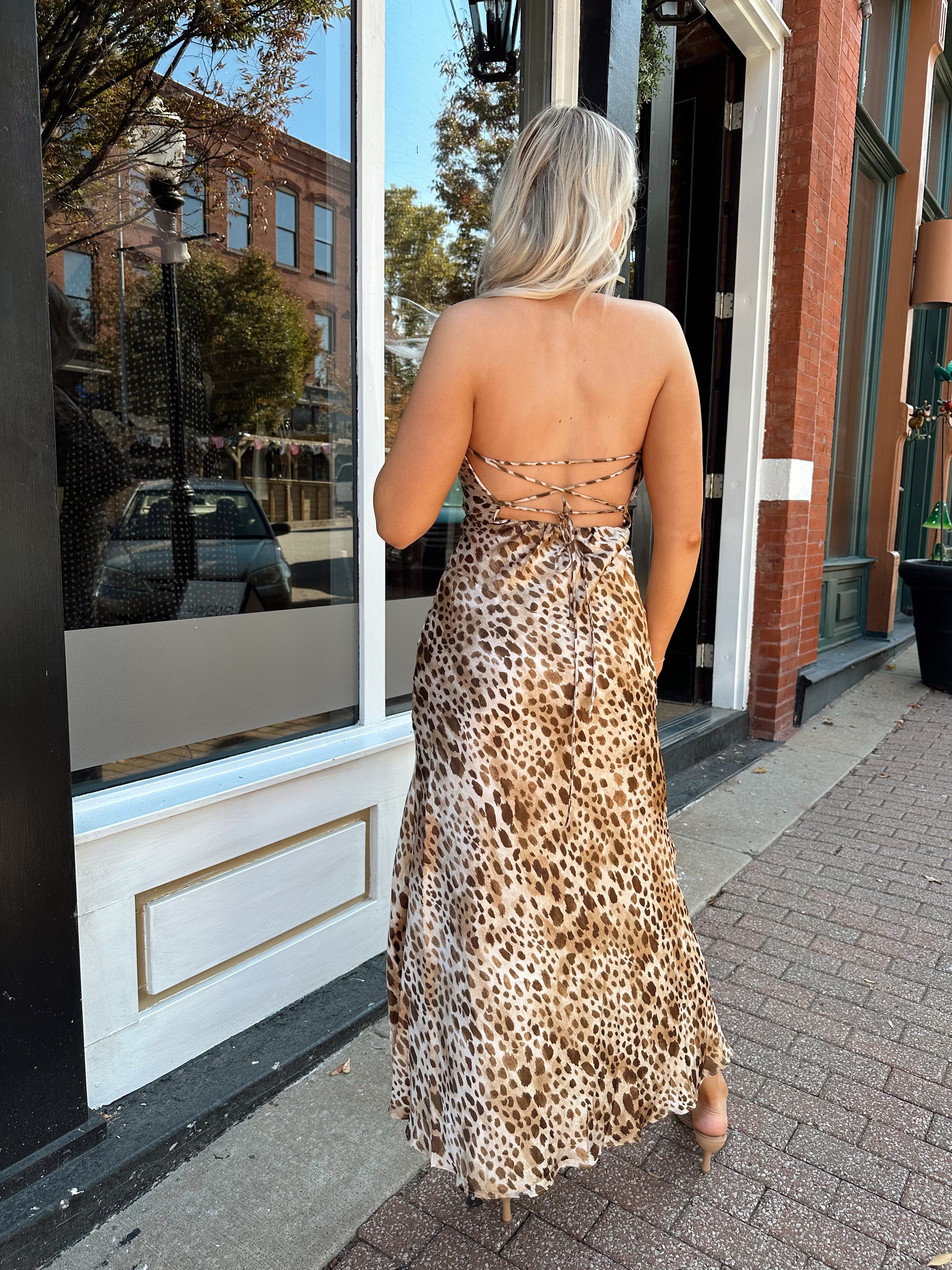 Woman wearing cheetah print satin maxi dress with cowl neckline, and lace up back.