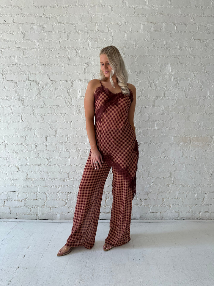 Woman wearing mauve and beige gingham two piece set with asymmetrical hem and lace trim.