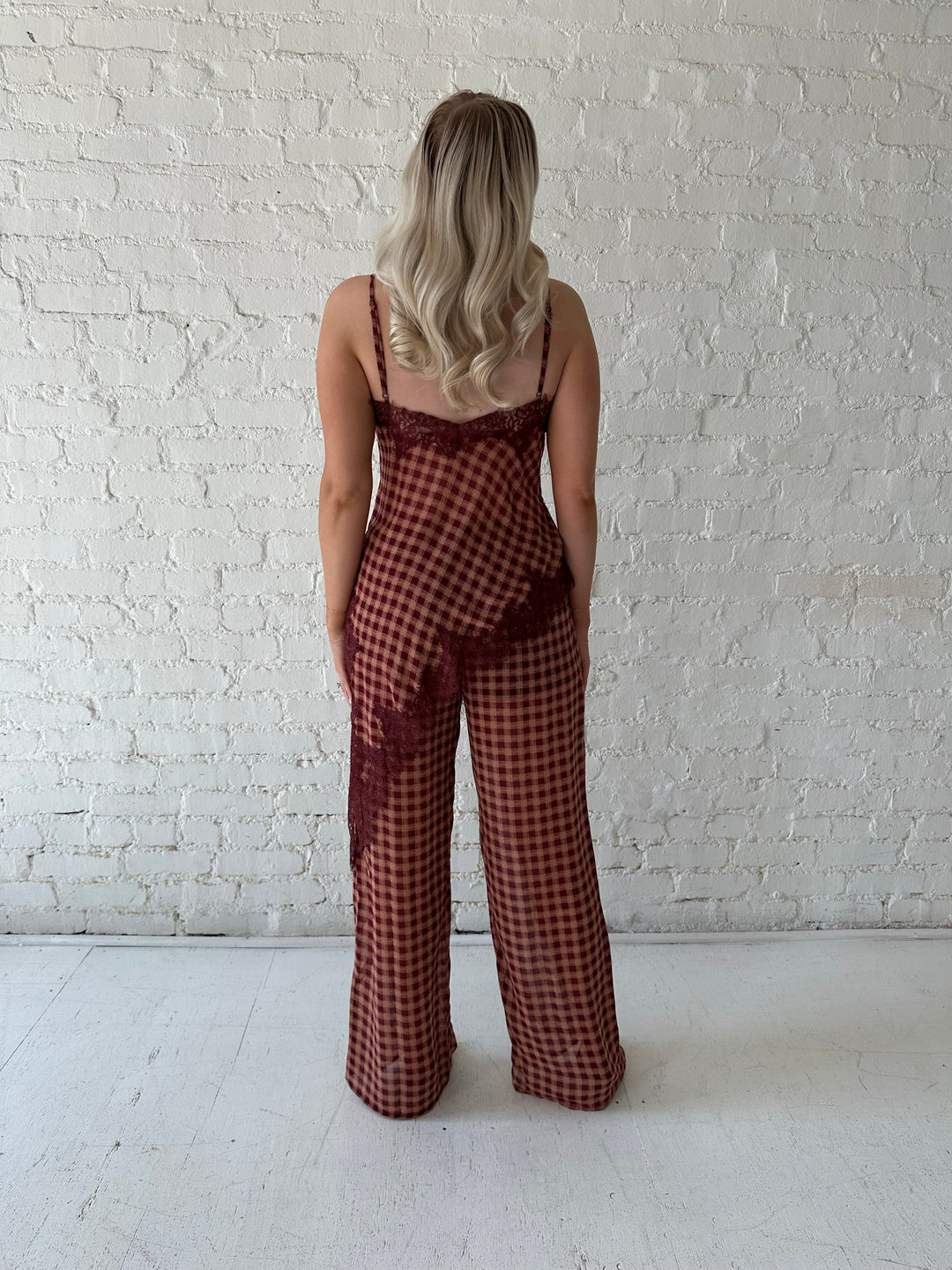 Woman wearing mauve and beige gingham two piece set with asymmetrical hem and lace trim.