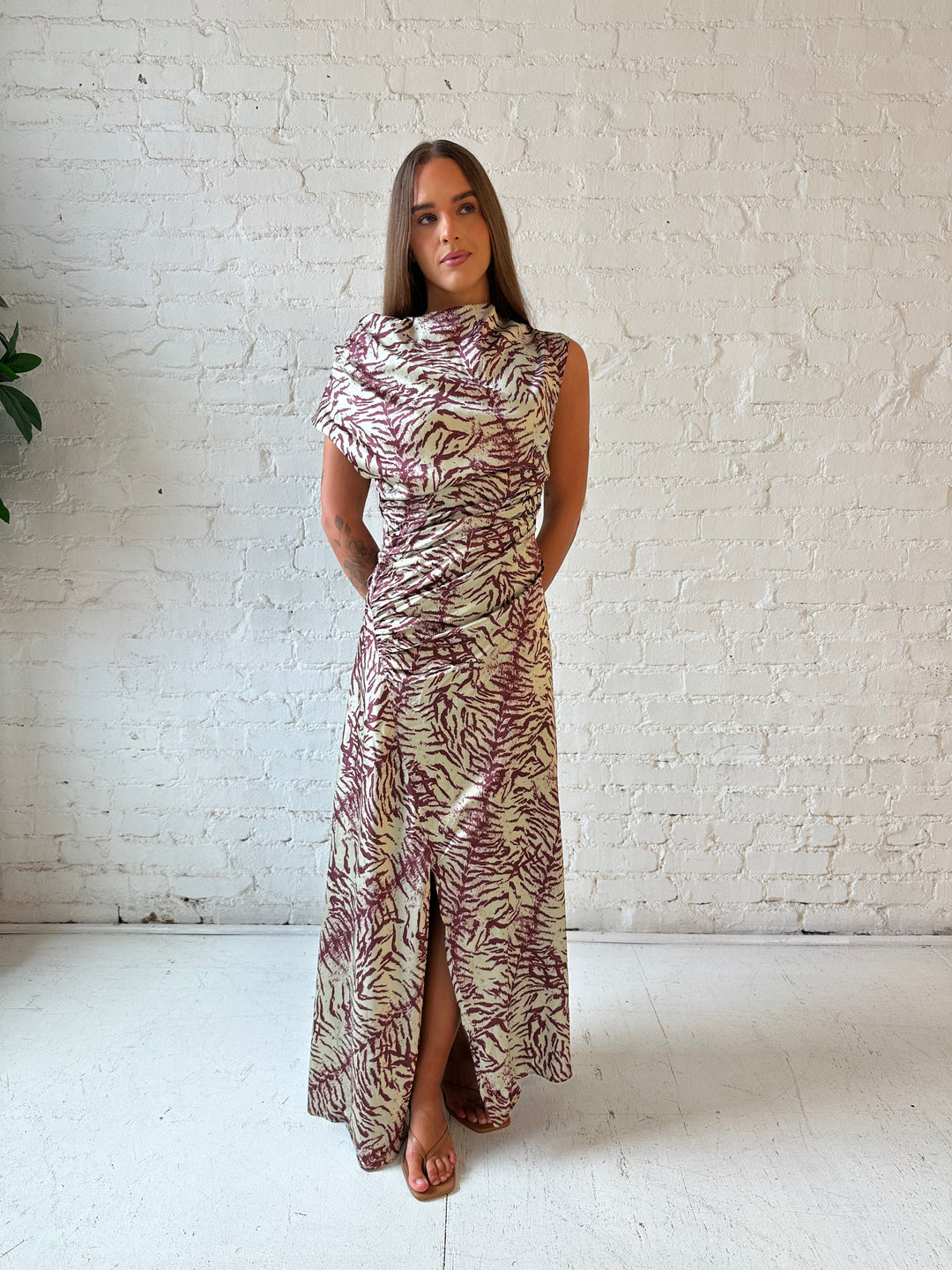 Woman wearing olive green animal print satin maxi dress with a high neckline, and side slit. 