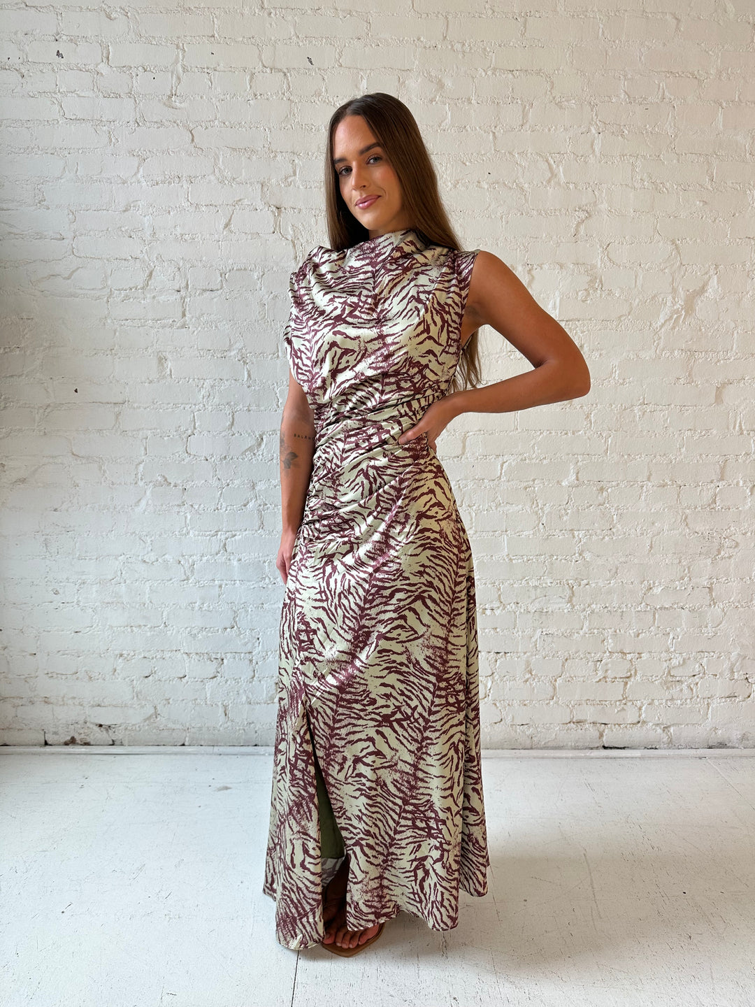 Woman wearing olive green animal print satin maxi dress with a high neckline, and side slit. 