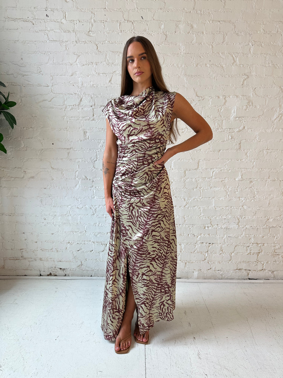 Woman wearing olive green animal print satin maxi dress with a high neckline, and side slit. 