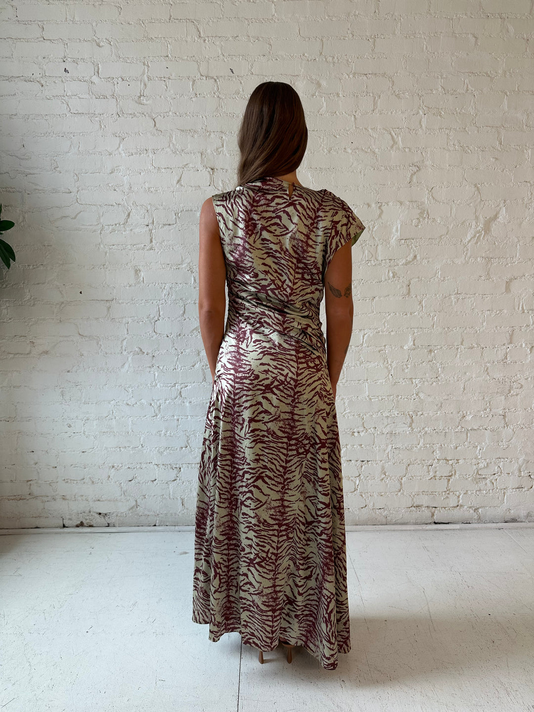 Woman wearing olive green animal print satin maxi dress with a high neckline, and side slit. 