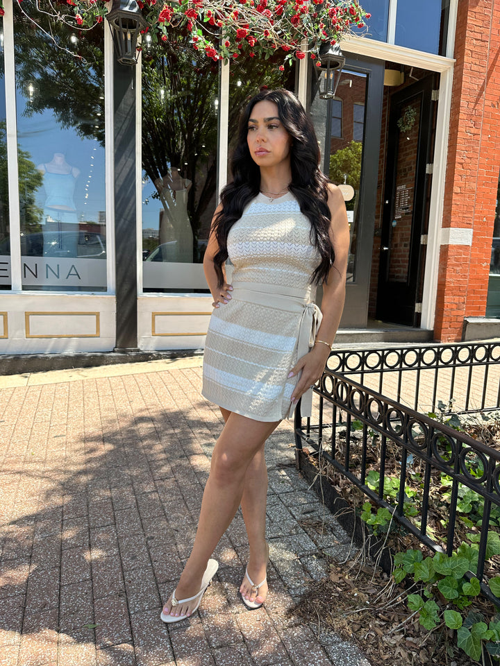 Woman wearing taupe and white striped knit two piece set with wrap skirt. 