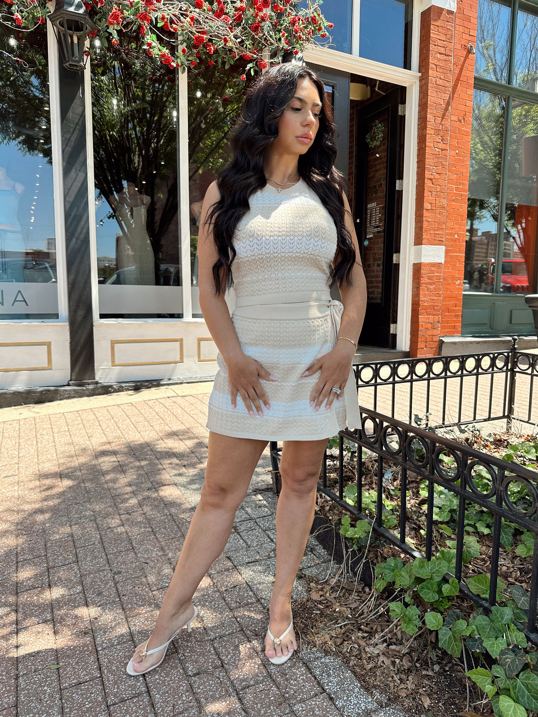 Woman wearing taupe and white striped knit two piece set with wrap skirt. 