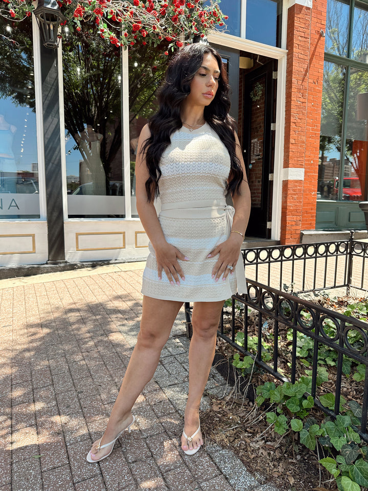 Woman wearing taupe and white striped knit two piece set with wrap skirt. 