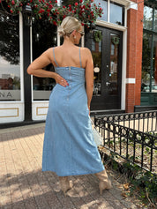 Woman wearing light wash denim midi dress with ivory lace embroidery detail and functional pockets.
