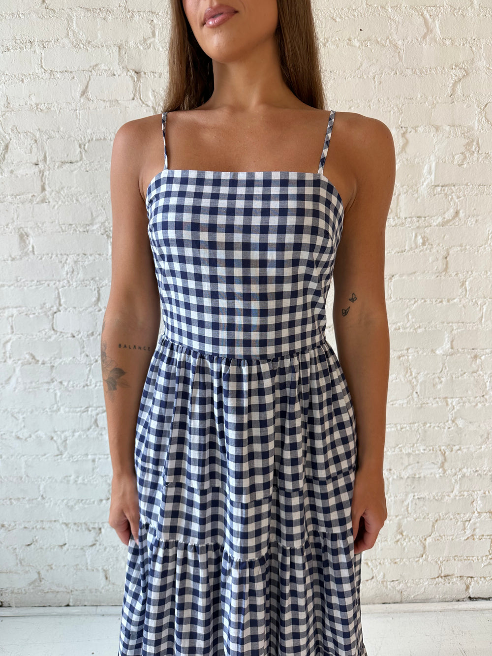 Woman wearing navy gingham midi dress with kitten heel.