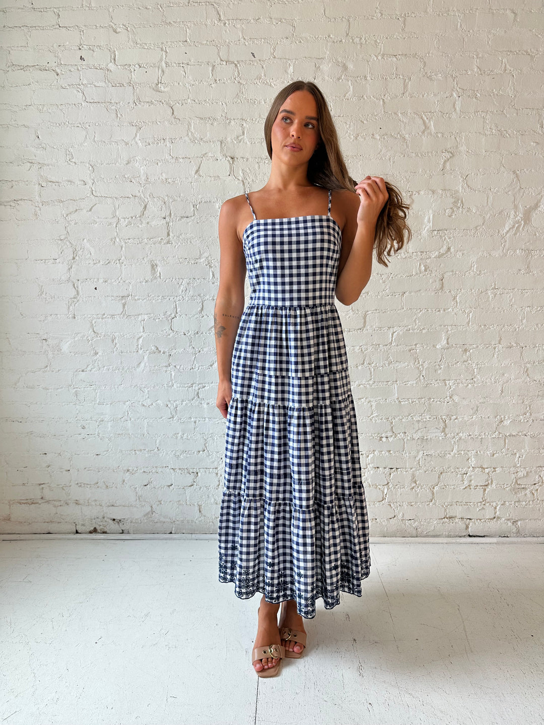 Woman wearing navy gingham midi dress with kitten heel.