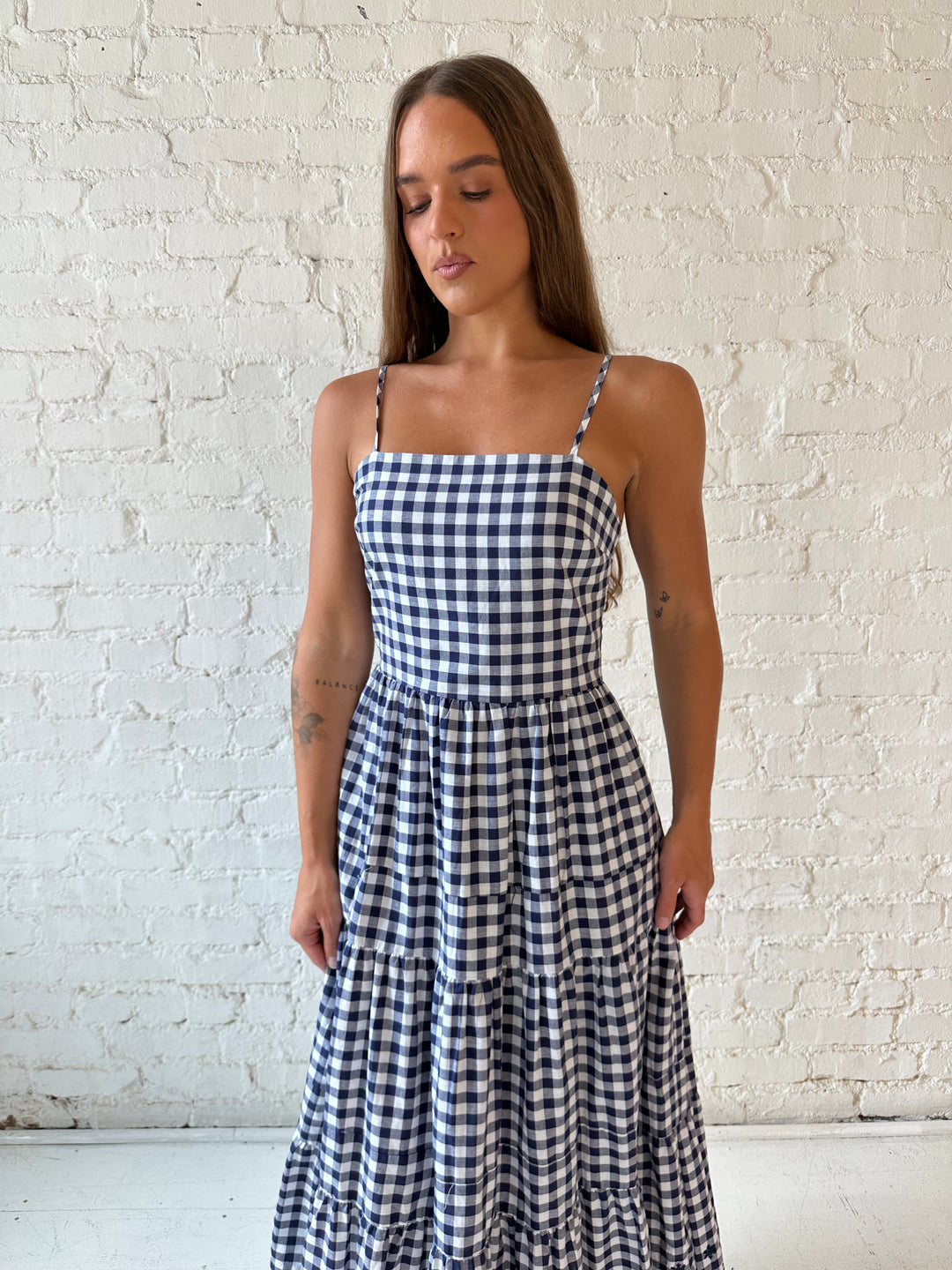 Woman wearing navy gingham midi dress with kitten heel.