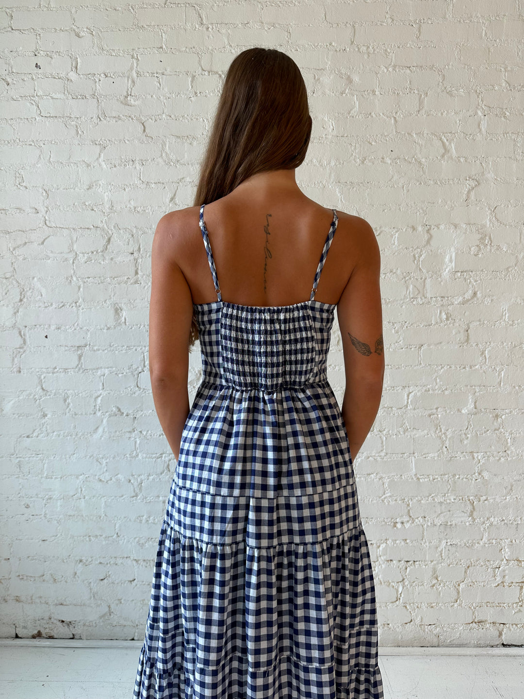 Woman wearing navy gingham midi dress with kitten heel.