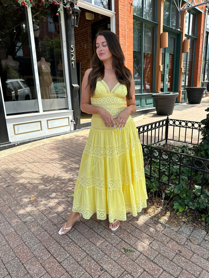 Woman wearing yellow textured maxi dress with v-neckline, adjustable straps and a tiered bottom. 