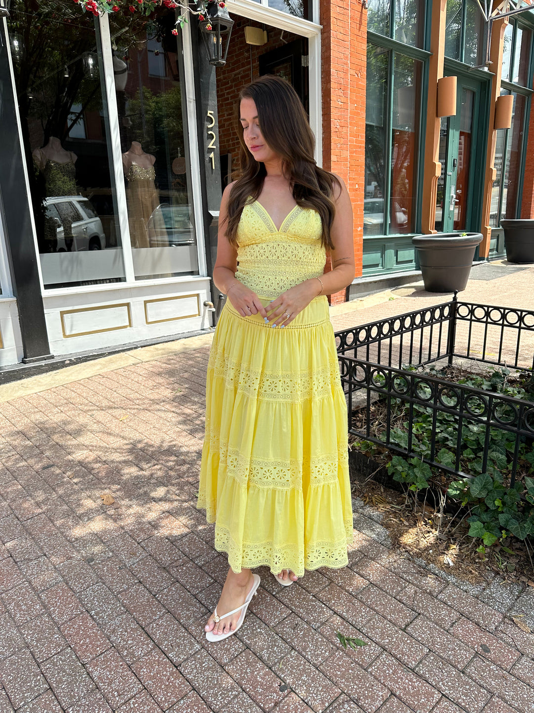 Woman wearing yellow textured maxi dress with v-neckline, adjustable straps and a tiered bottom. 