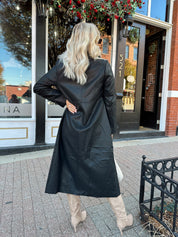 Woman wearing black tailored trench coat and knit sweater mini dress.