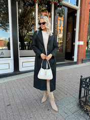 Woman wearing black tailored trench coat and knit sweater mini dress.