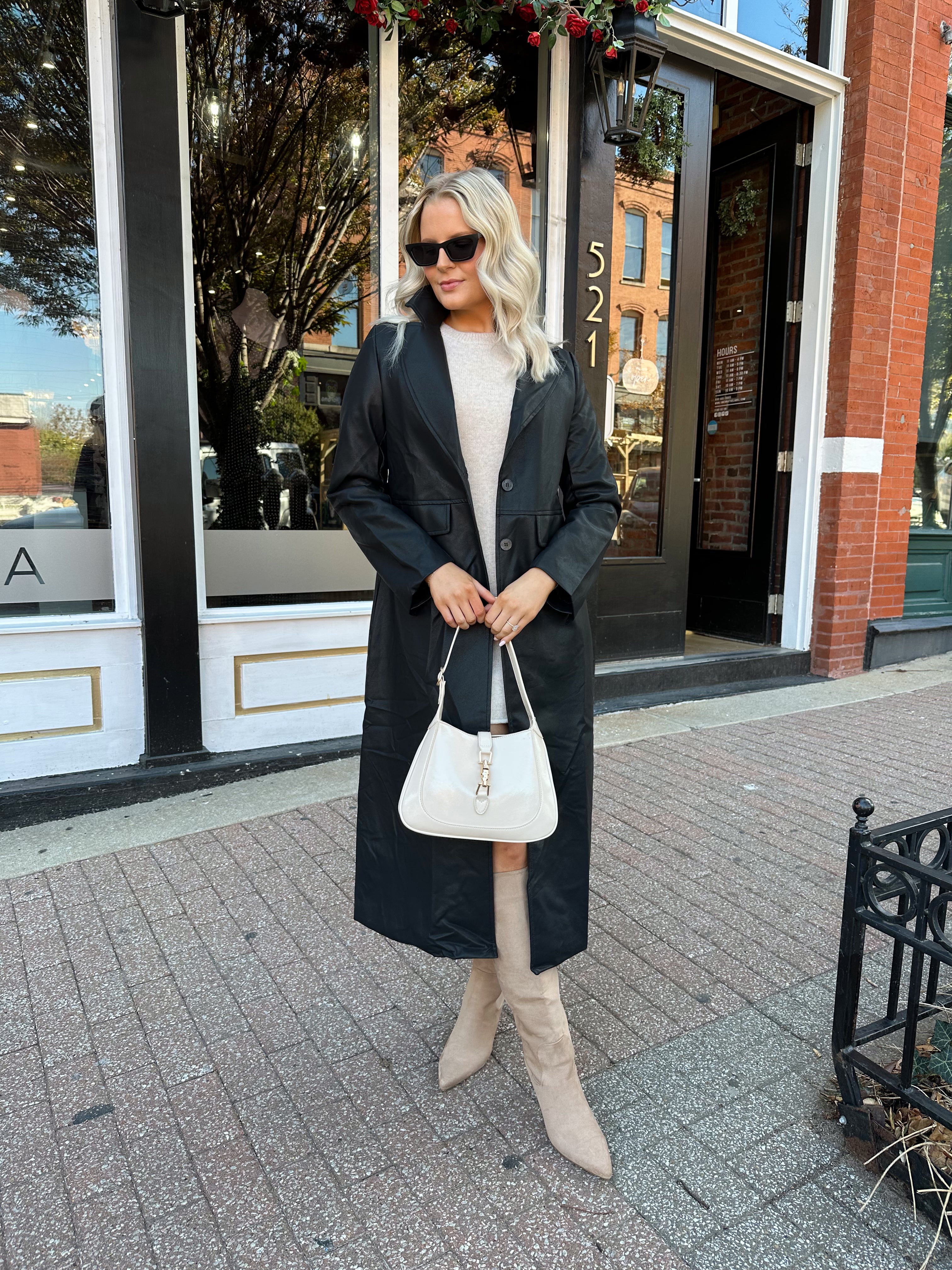 Woman wearing black tailored trench coat and knit sweater mini dress.