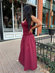 Woman wearing burgundy halter maxi dress with contrast material. 