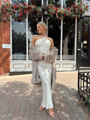Woman wearing off white satin maxi dress with lace trim detailing, and self tie halter neck. 