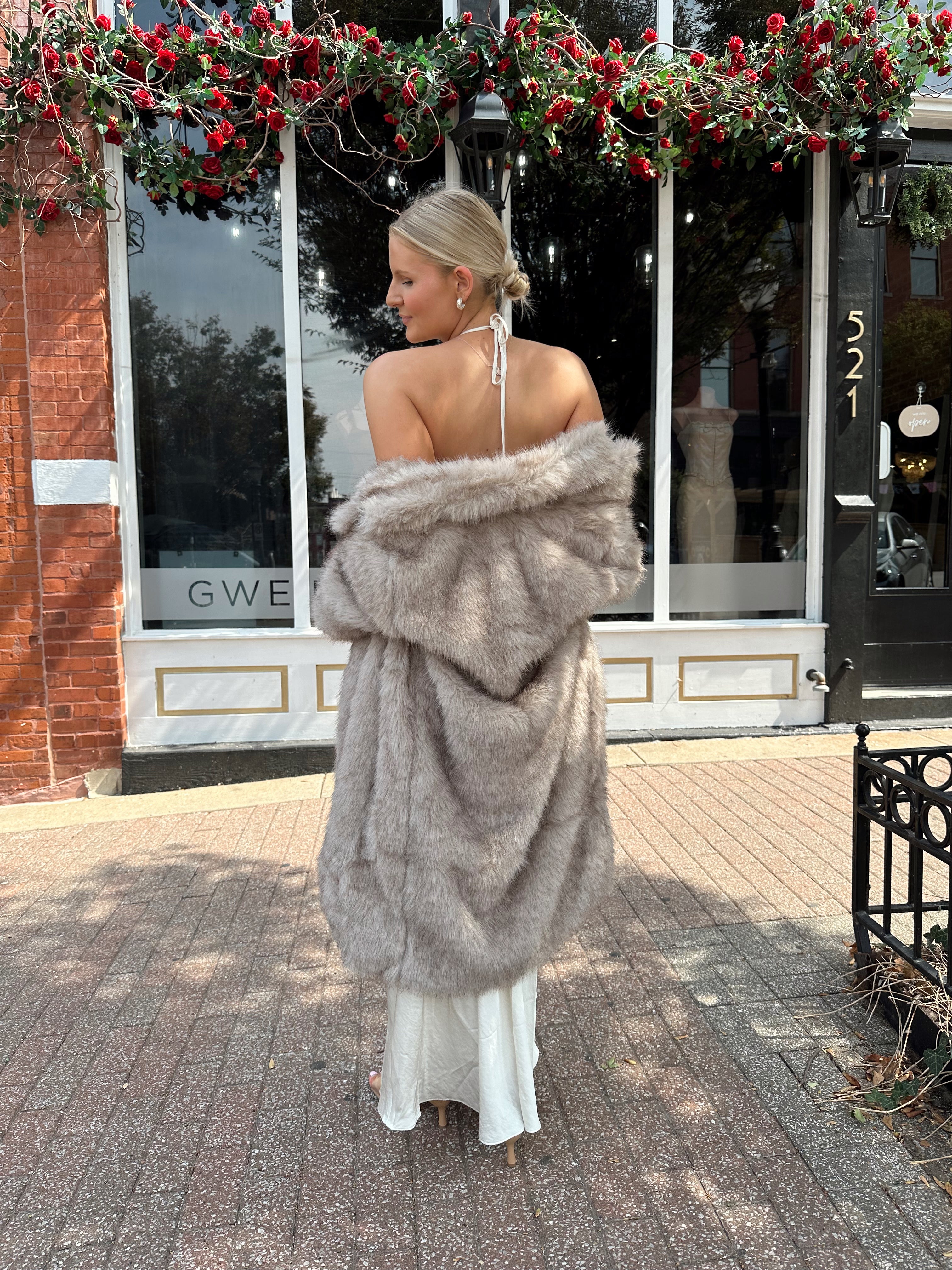 Woman wearing off white satin maxi dress with lace trim detailing, and self tie halter neck. 