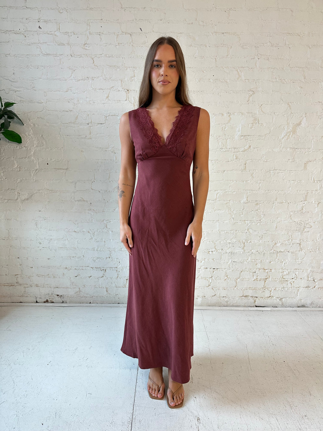 Woman wearing mahogany midi dress with v-neckline and lace trim detail with tie back.