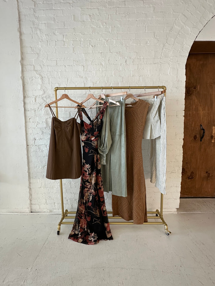 Neutral fall statement clothing pieces hanging on a rack.