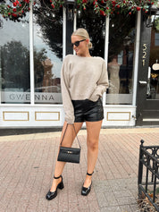 Woman wearing black high waisted faux leather shorts. 