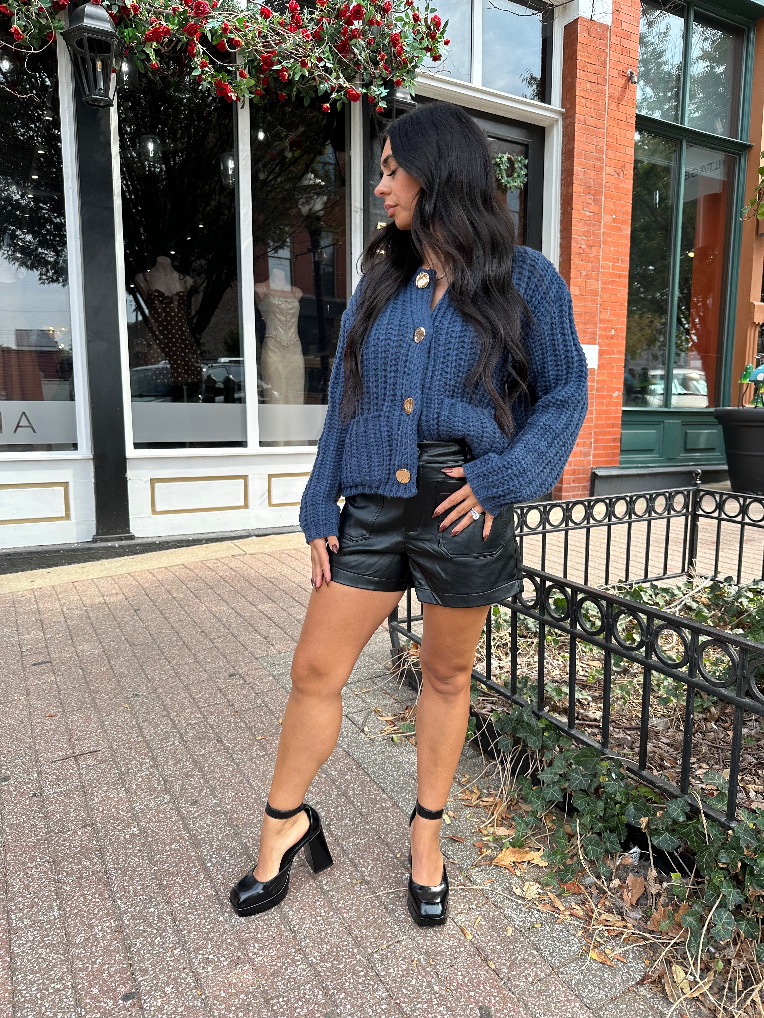 Woman wearing black high waisted faux leather shorts. 