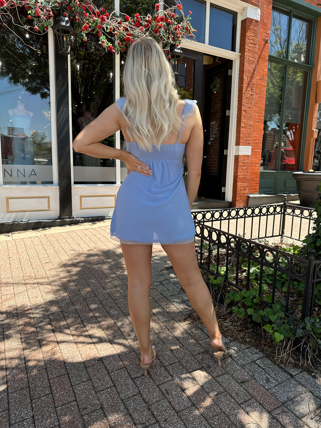 Woman wearing blue chiffon slip dress with trim detailing and adjustable straps. 