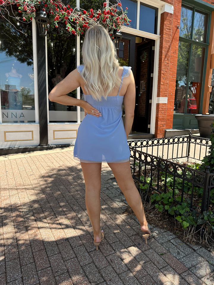 Woman wearing blue chiffon slip dress with trim detailing and adjustable straps. 
