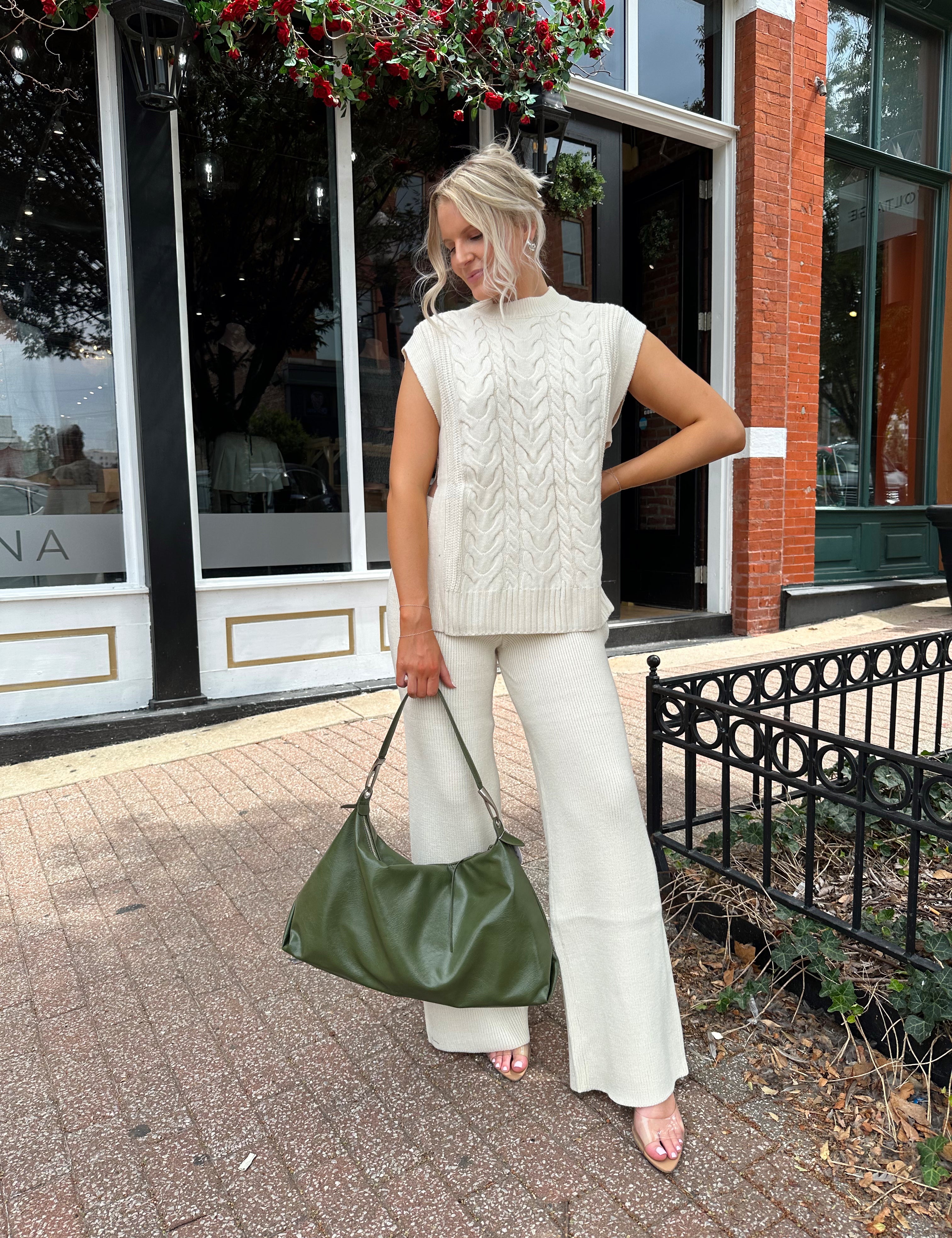 Woman wearing cream two piece sweater set with open side detailing. 
