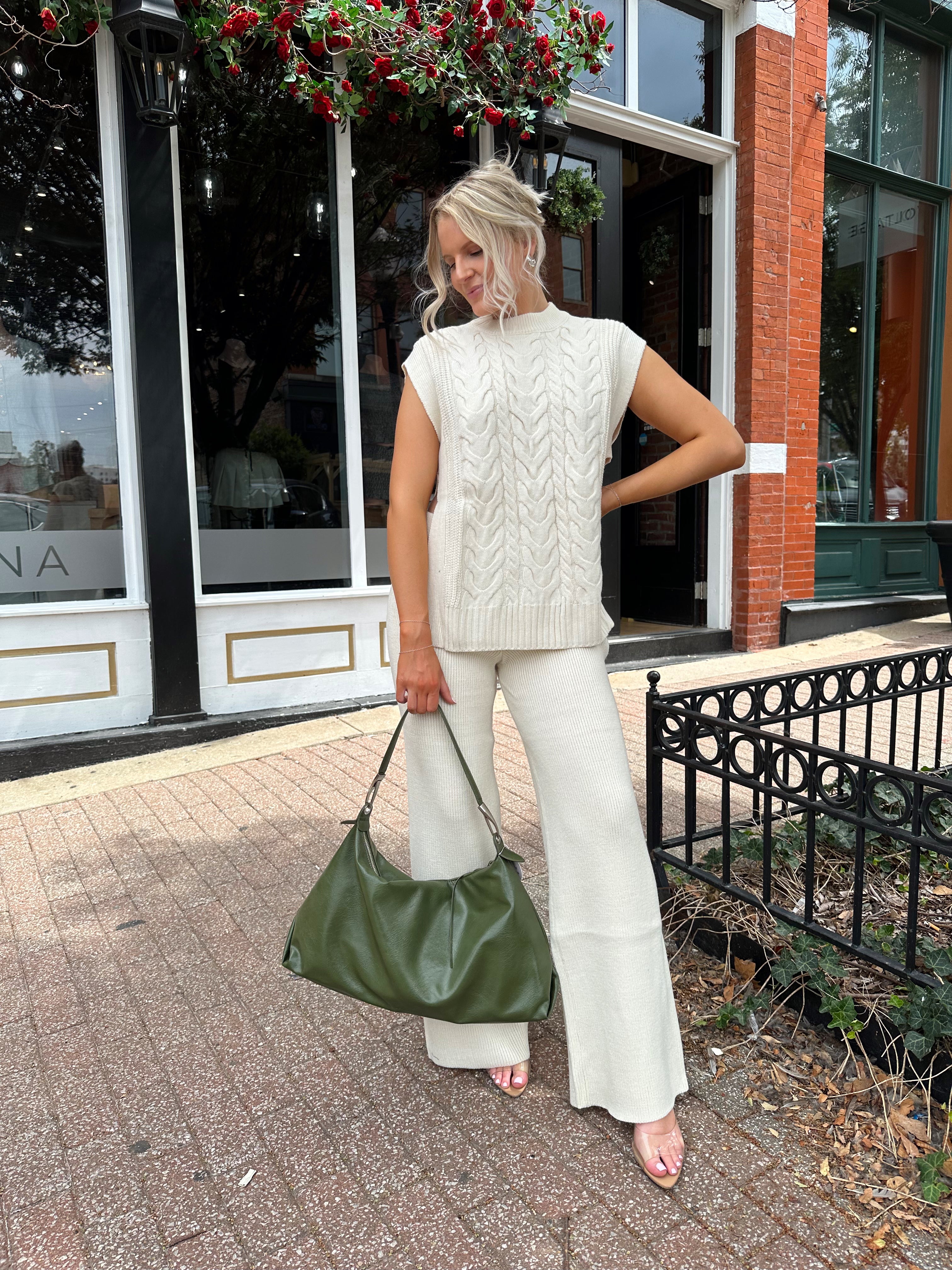 Woman wearing cream two piece sweater set with open side detailing. 
