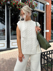 Woman wearing cream two piece sweater set with open side detailing. 