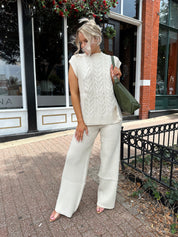 Woman wearing cream two piece sweater set with open side detailing. 