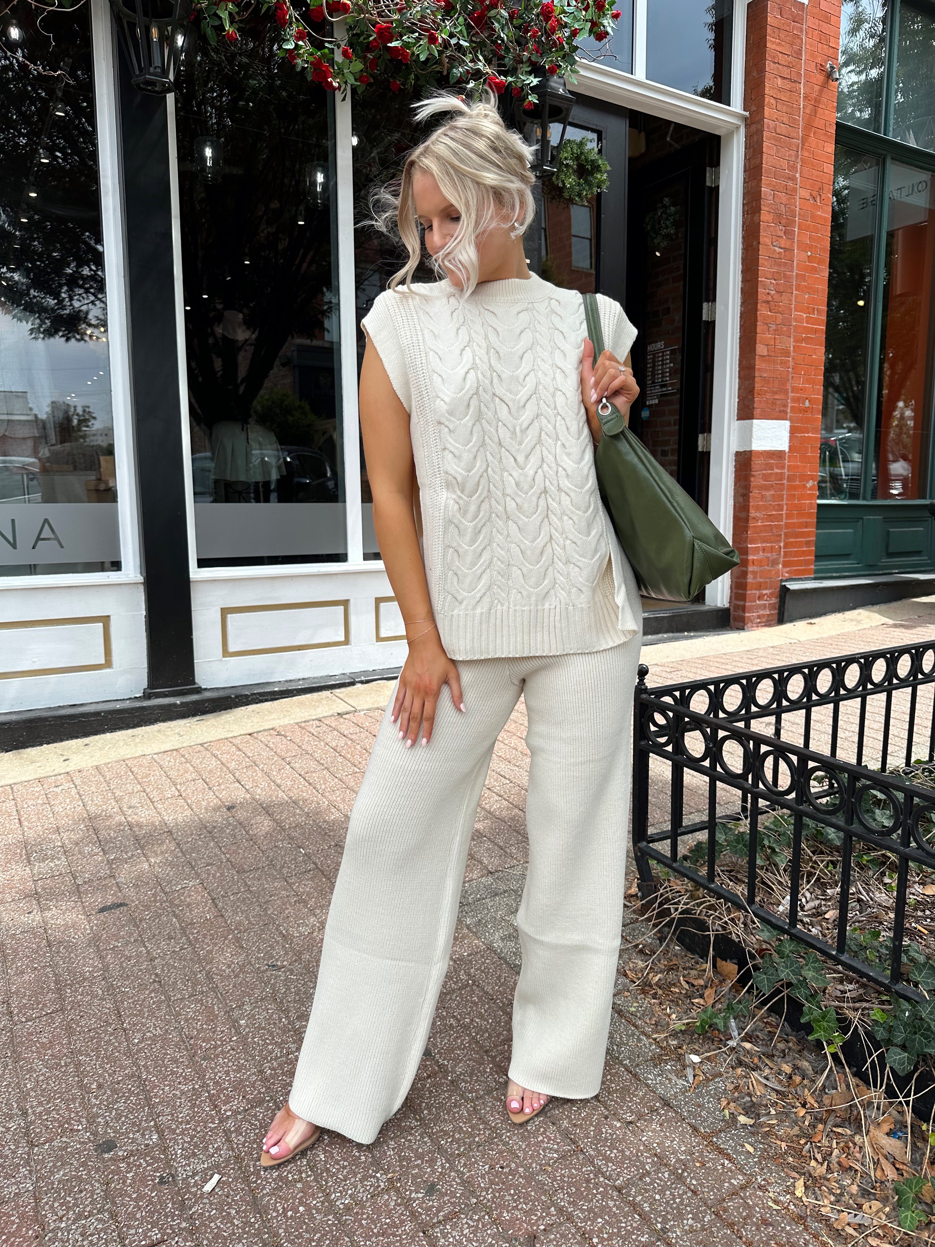 Woman wearing cream two piece sweater set with open side detailing. 