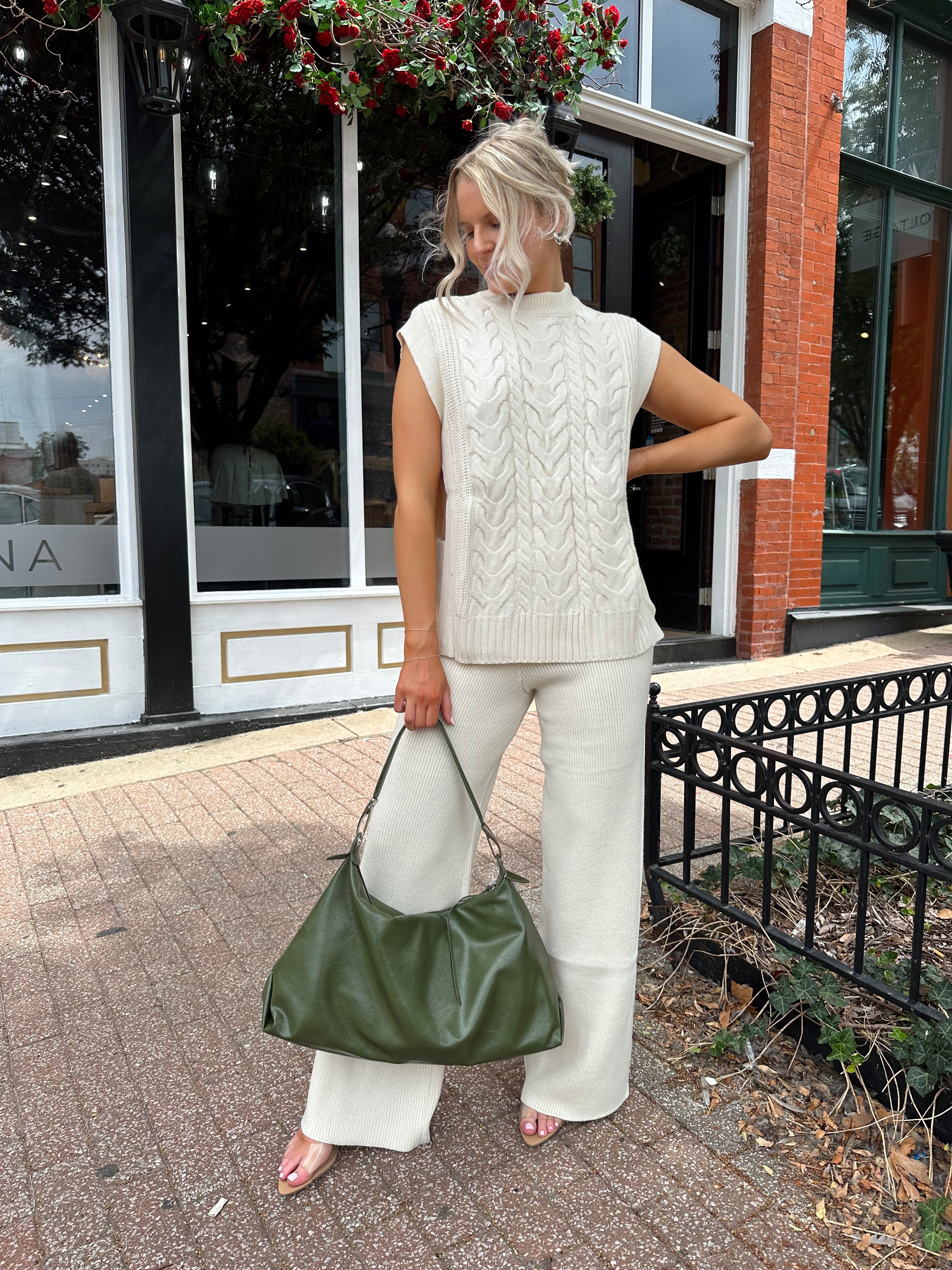 Woman wearing cream two piece sweater set with open side detailing. 