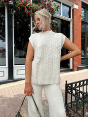 Woman wearing cream two piece sweater set with open side detailing. 