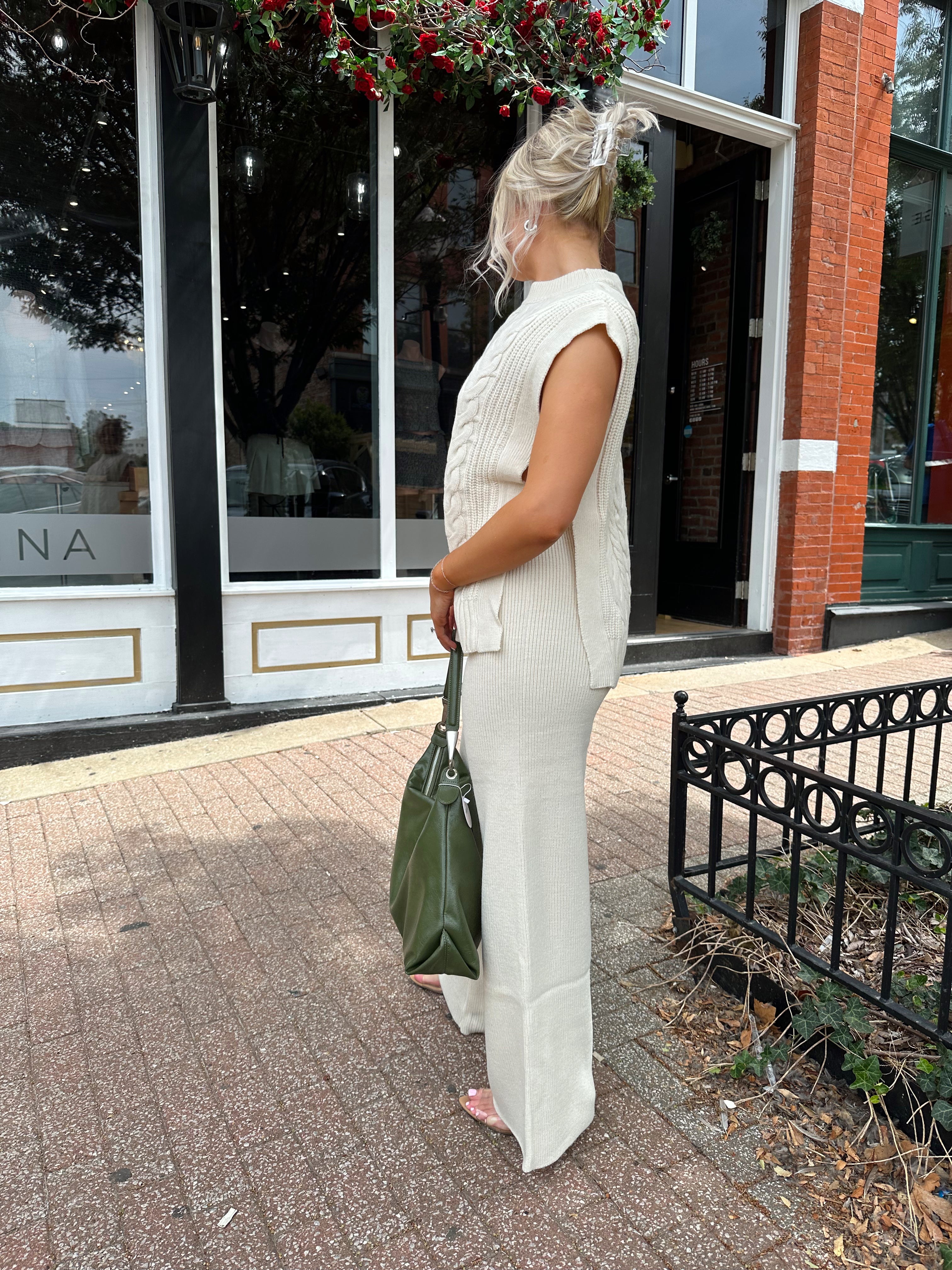 Woman wearing cream two piece sweater set with open side detailing. 