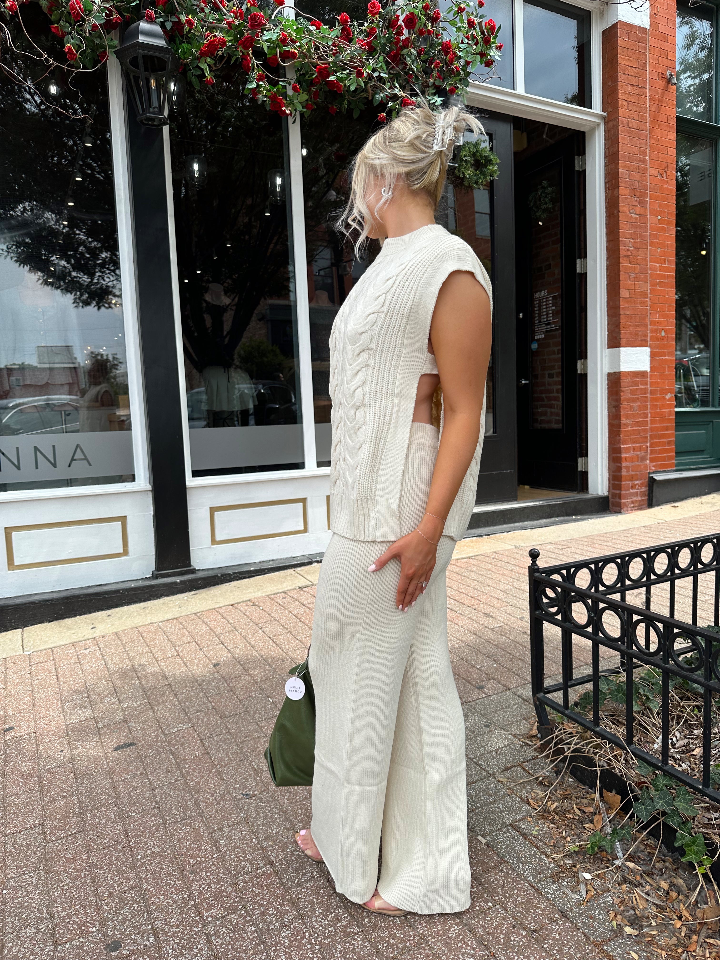 Woman wearing cream two piece sweater set with open side detailing. 